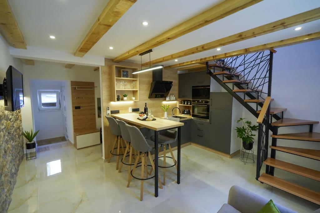 una cocina con una isla con taburetes y una escalera de caracol en Apartment Ispod ure, en Sinj