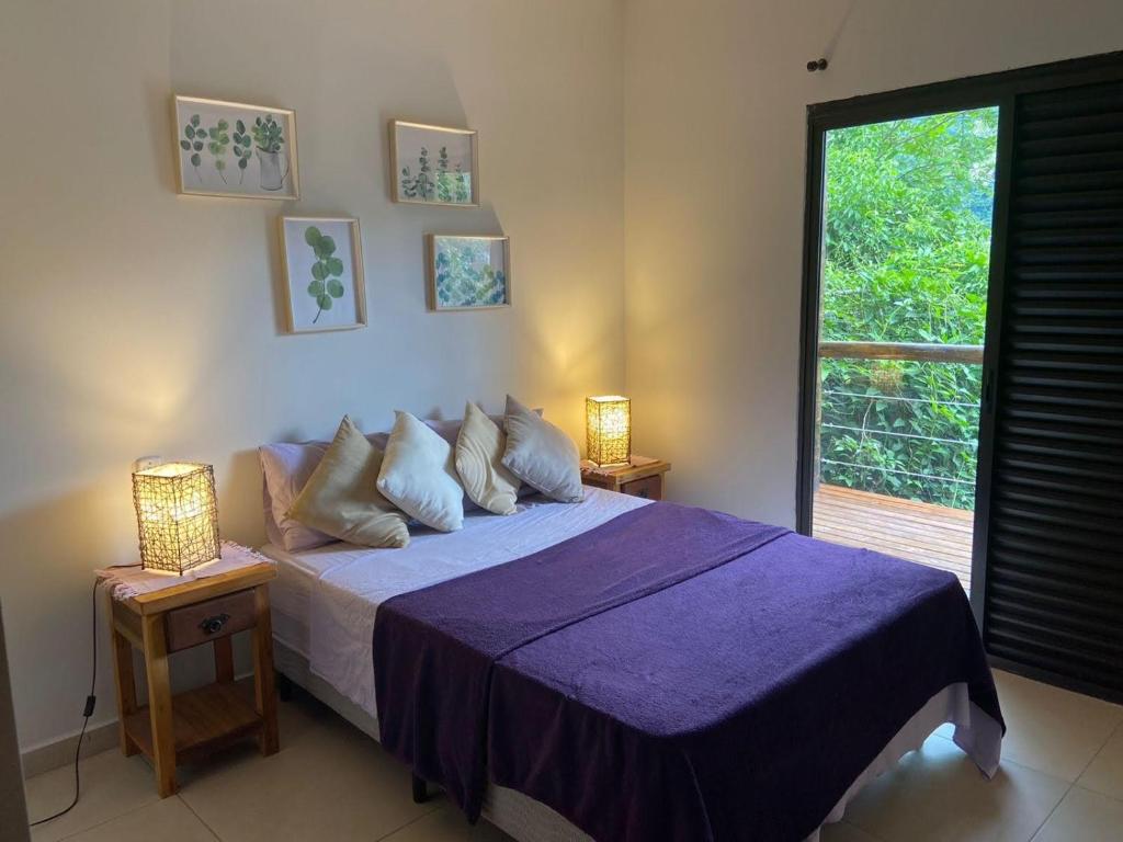 una camera con letto viola e finestra di Suíte aconchegante a Ilhabela