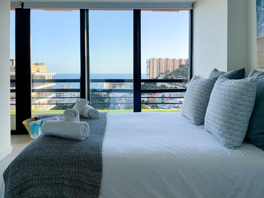 Tyba Deluxe Apartment في أليكانتي: غرفة نوم بسرير ابيض كبير مع نوافذ كبيرة