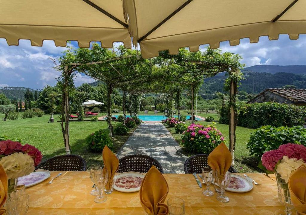 tavolo con sedie e ombrellone e piscina di Casa del Fattore by MC Luxury Rentals a Capannori