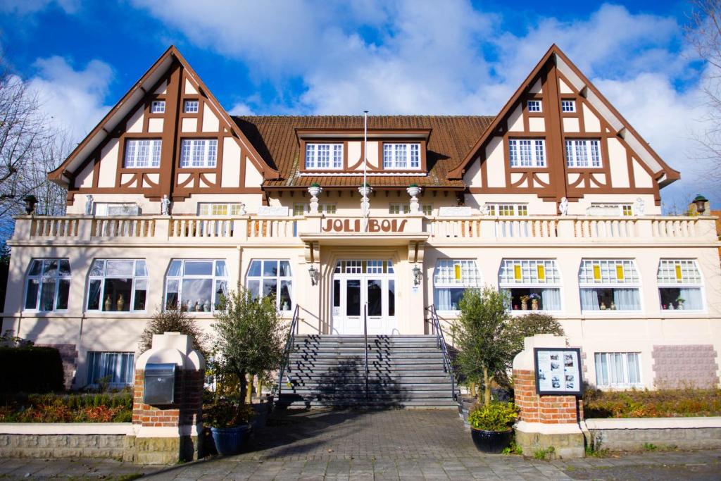 un grand bâtiment blanc avec un toit en gambrel dans l'établissement Boutique Hotel Joli Bois, au Coq