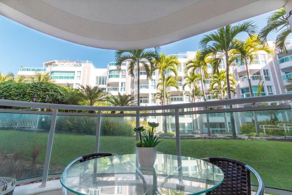 una mesa de cristal y sillas en un balcón con palmeras en In Mare #26 - Apartamento na Praia por Carpediem, en Parnamirim
