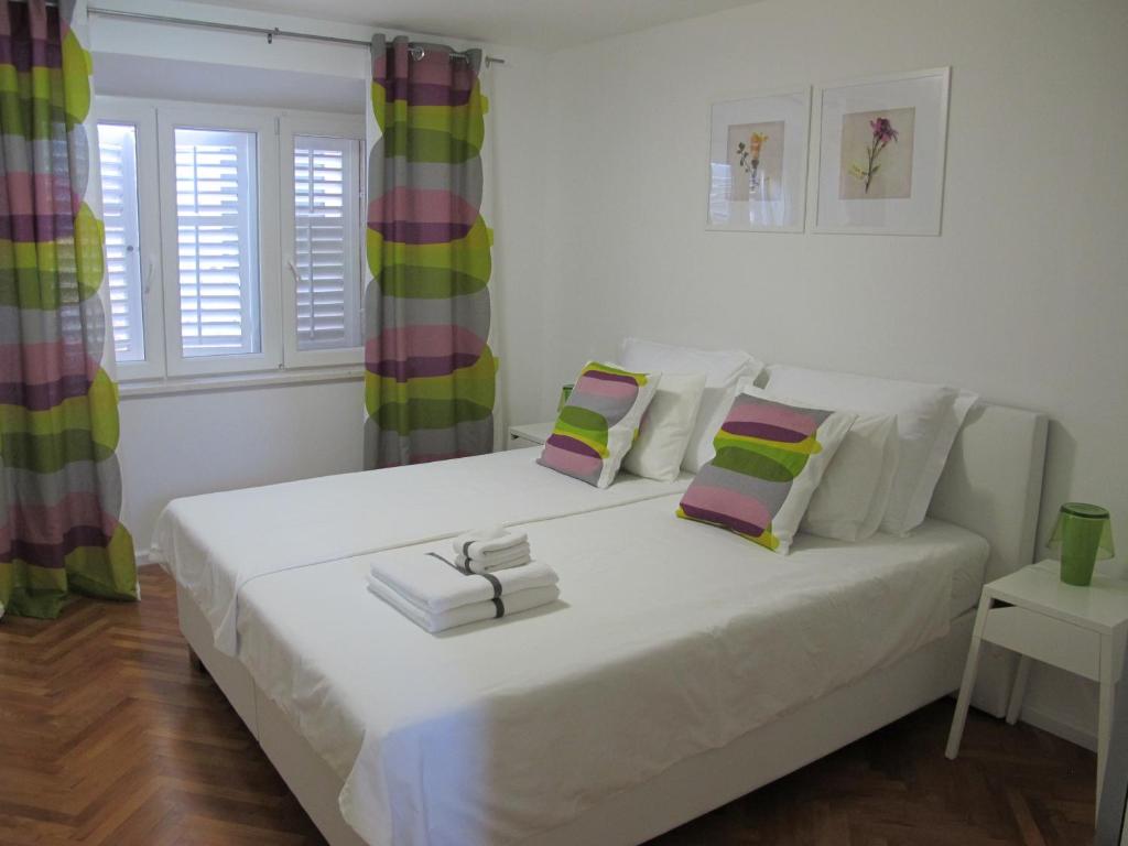 a bedroom with a large white bed with books on it at Fiorino Rooms Korčula in Korčula