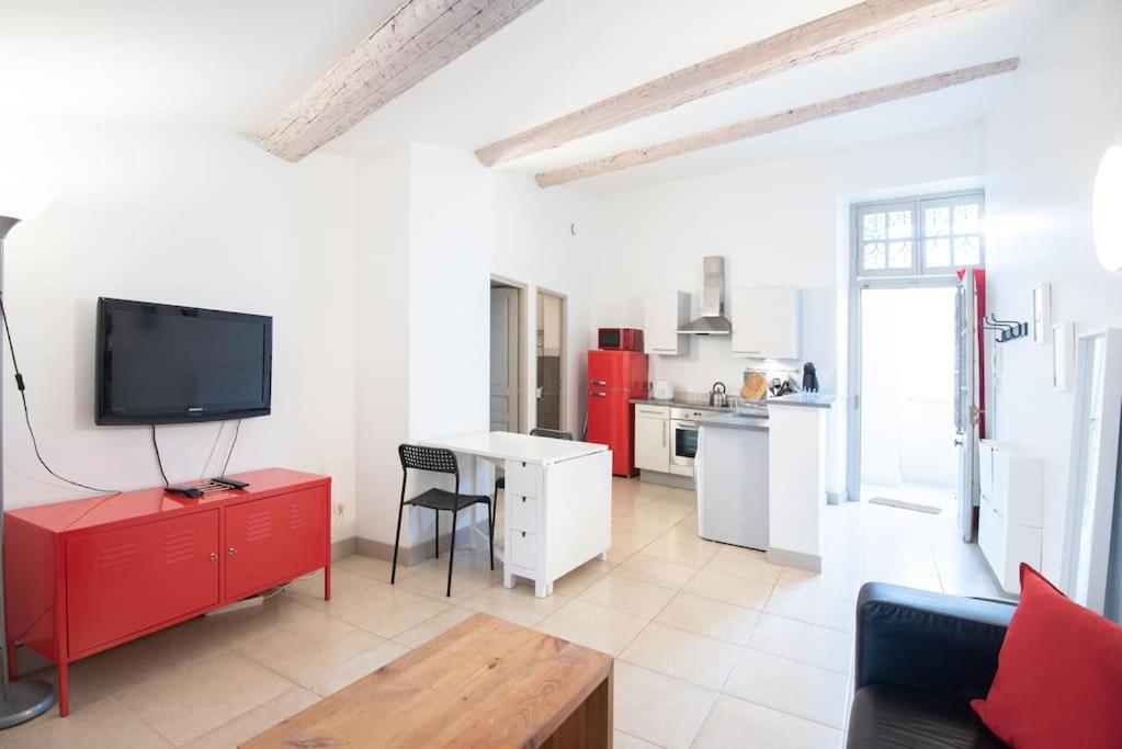 a living room with a red cabinet and a kitchen at Domus Arena, parking, wifi, arènes in Nîmes