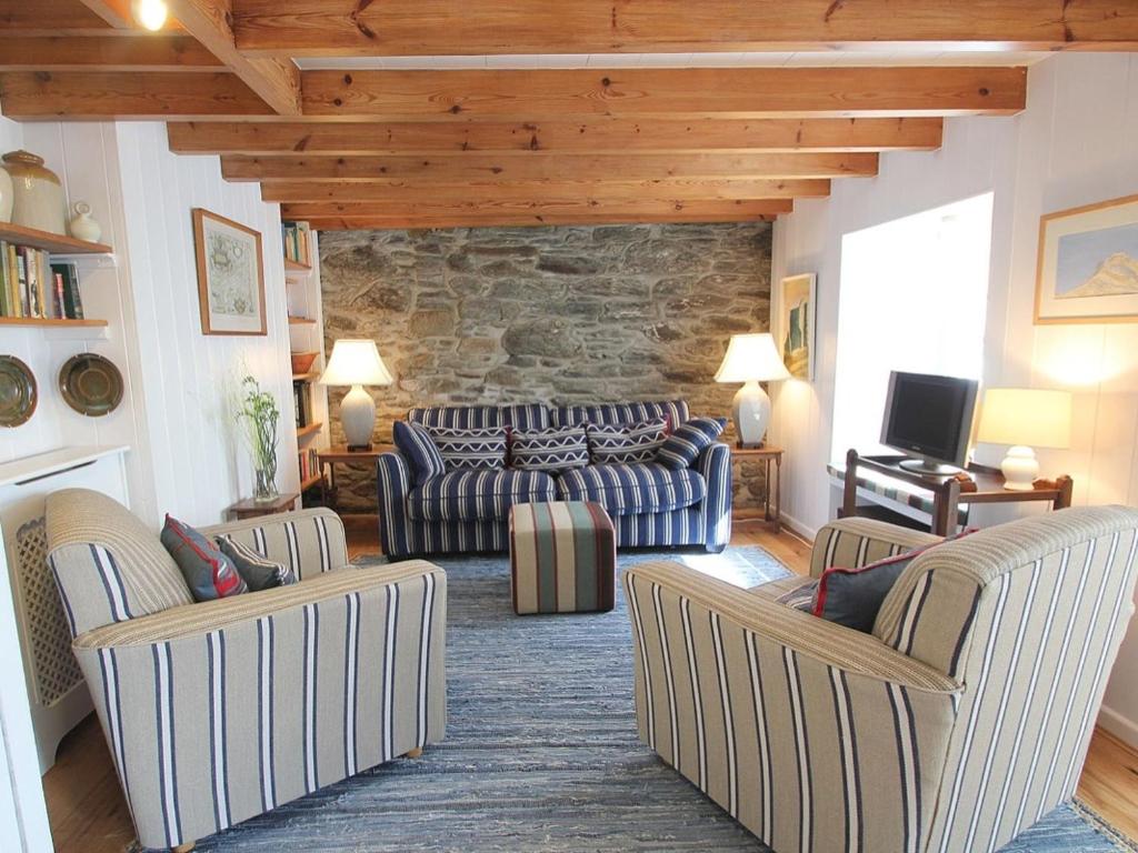 a living room with couches and a stone wall at Pegs in Porthleven
