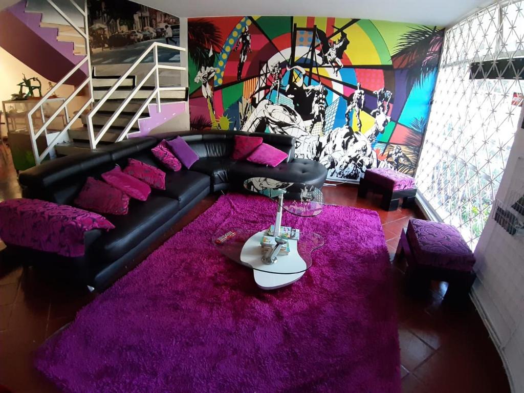 een woonkamer met een zwarte bank en een paars tapijt bij Hotel COMIC CITY in Bogota