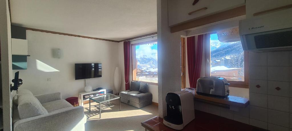 ein Wohnzimmer mit einem Sofa, einem TV und einem Fenster in der Unterkunft Résidence Saboia Courchevel La Tania - Belle Vue in Courchevel