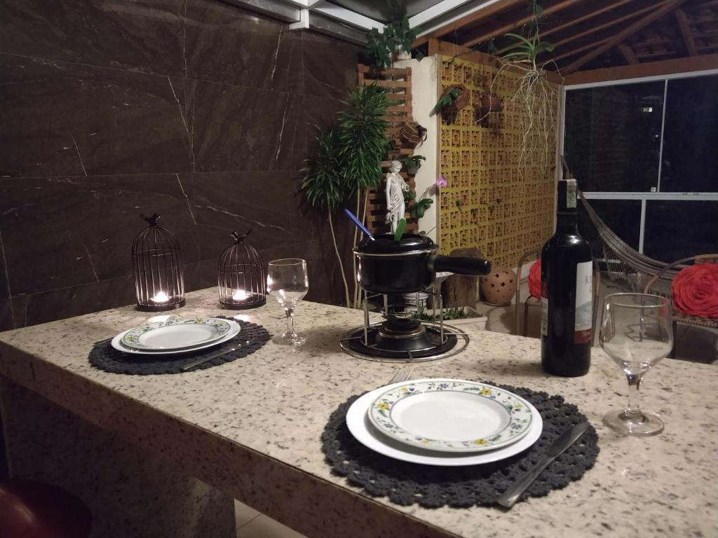 a table with two plates and wine glasses on it at Recanto das Orquídeas Domingos Martins- Soido De Cima,4km centro in Domingos Martins