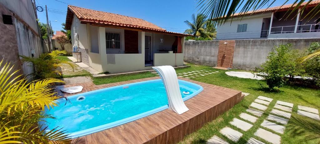 a swimming pool with a white chair in a yard at Casa de praia para temporada - Guriri in São Mateus
