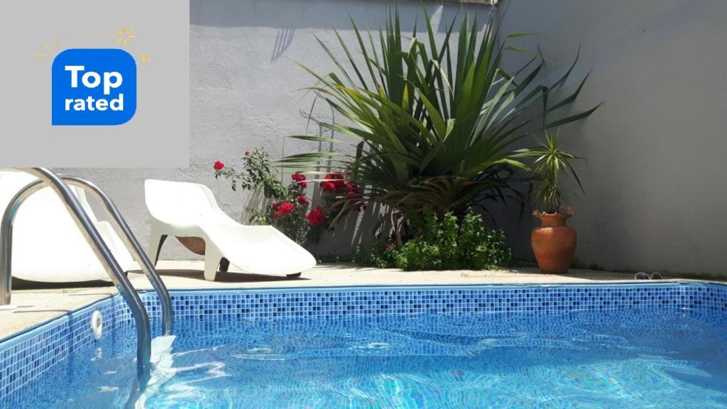 une piscine avec une chaise blanche, une chaise et des plantes dans l'établissement Hospedagem Lirio, à Bragança Paulista