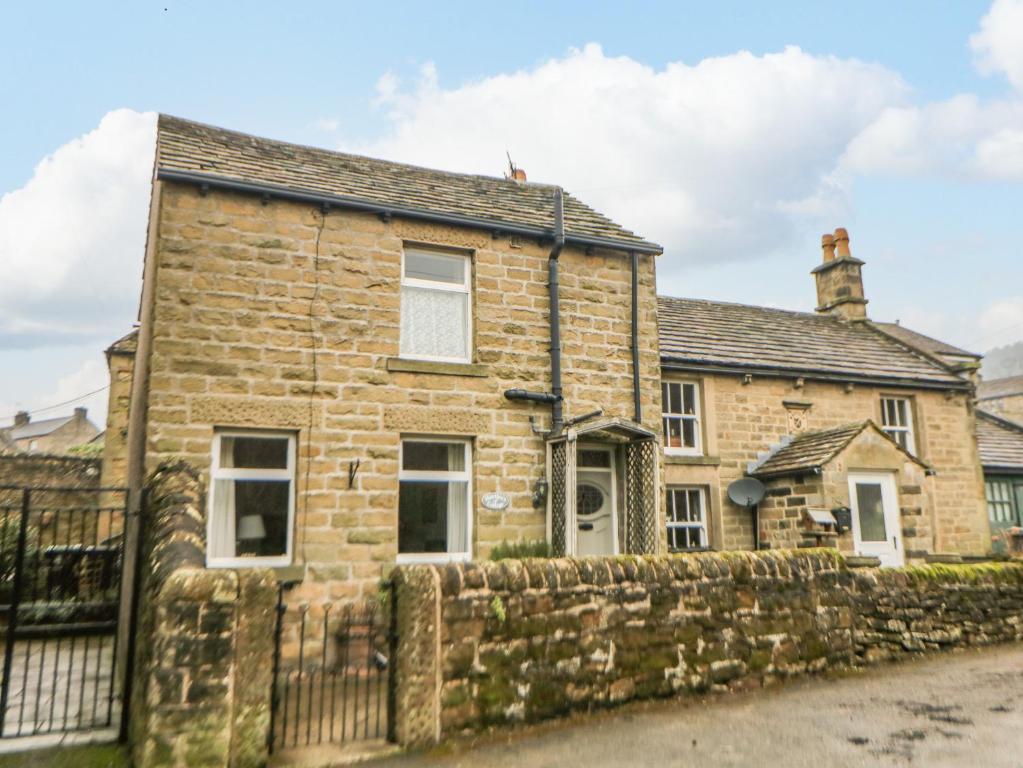 an old stone house with a fence at Hawthorn Cottage in Eyam