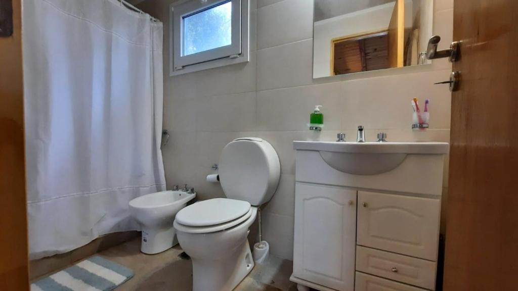 a white bathroom with a toilet and a sink at Claro del Bosque in San Carlos de Bariloche
