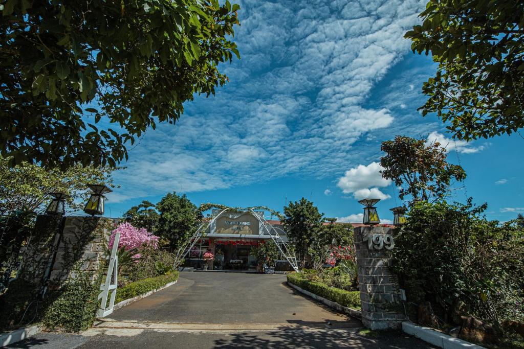 een oprit naar een huis met een bewolkte lucht bij Nhat Quang Hotel in Bao Loc