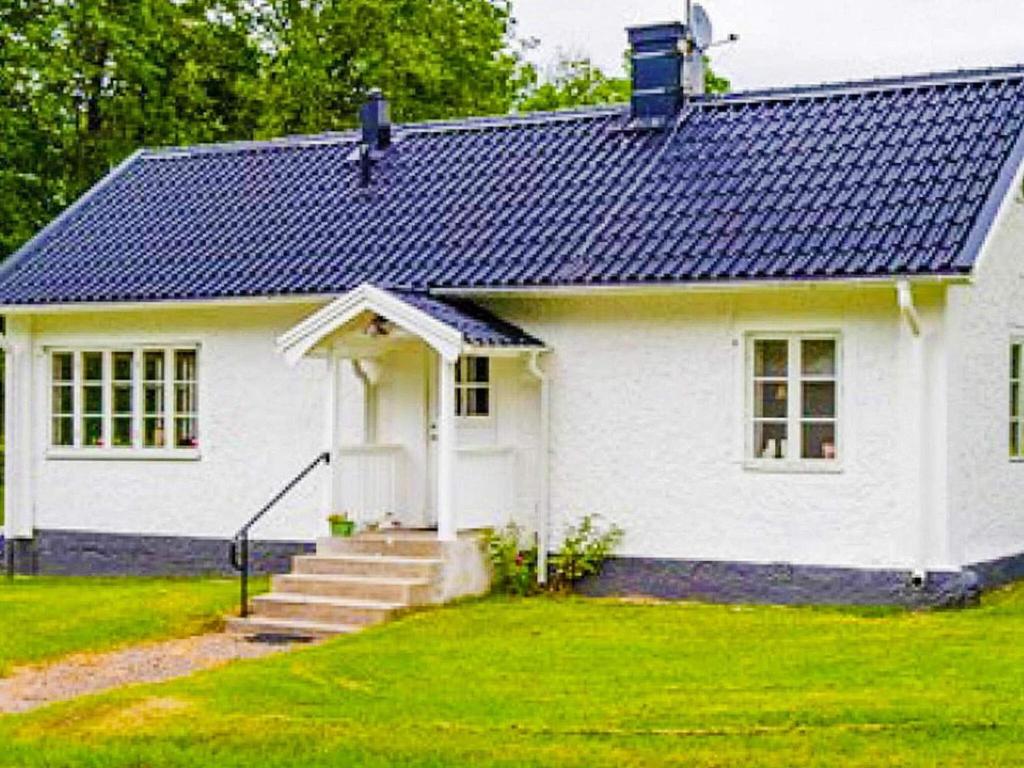 ein weißes Haus mit blauem Dach in der Unterkunft Holiday home ÅSBRO II in Åsbro