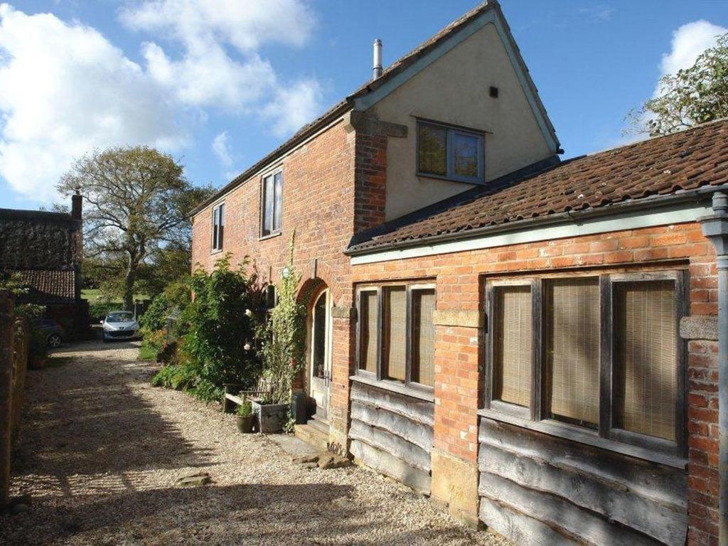 a brick house with a car parked in front of it at Pittards Farm Cottage in Lambrook