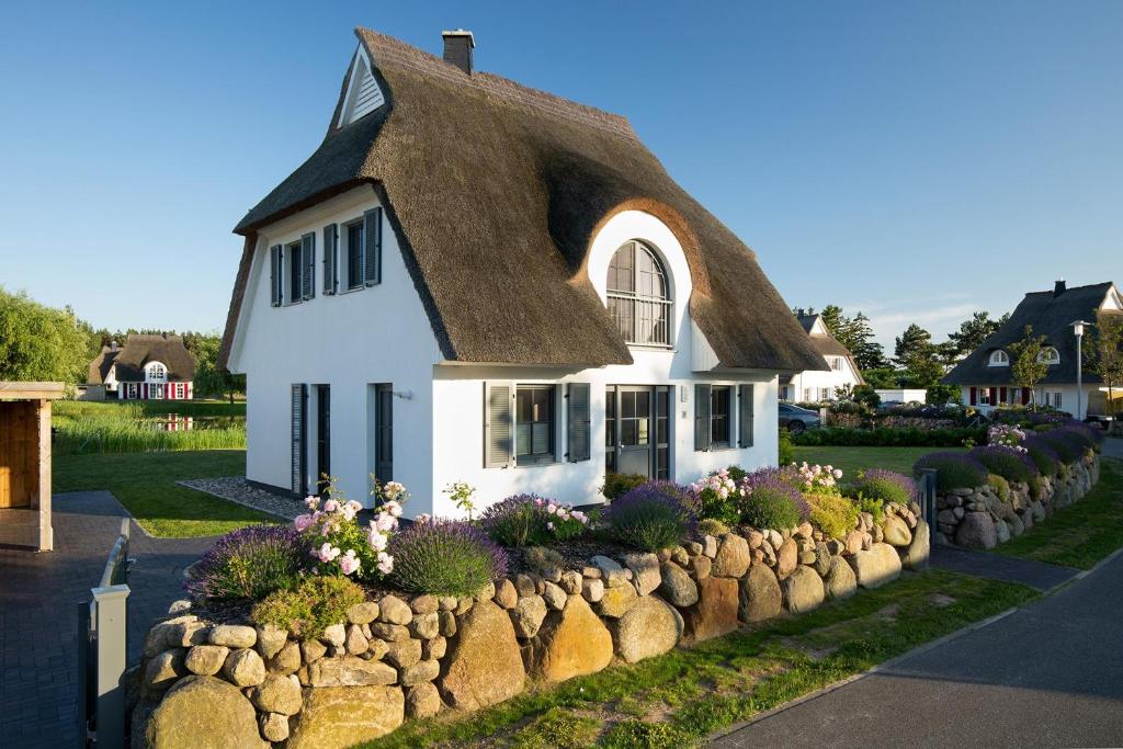 a small white house with a thatched roof at Ferienhaus Schilfrohrsaenger 54 in Fuhlendorf