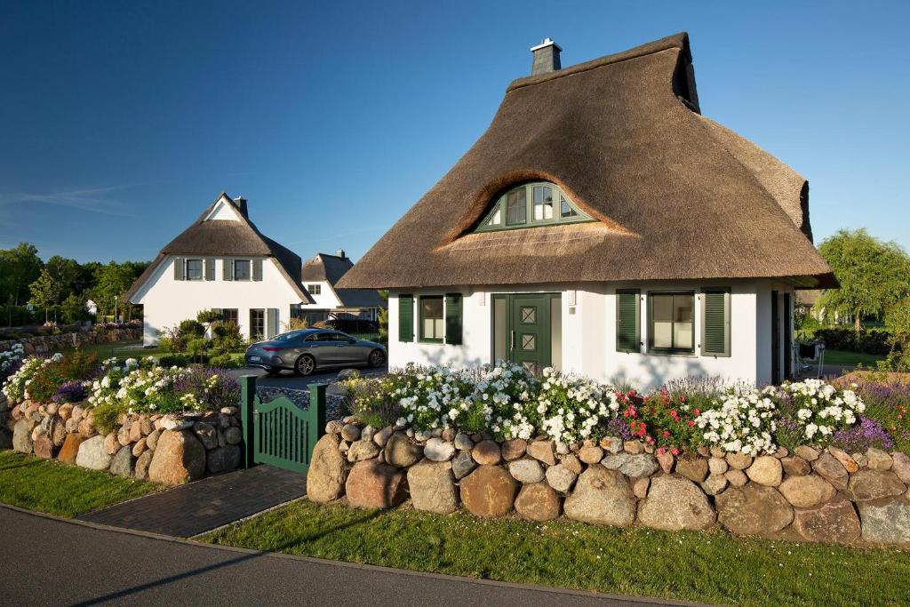 a house with a thatched roof and a flower garden at Ferienhaus Seeadler 65 in Fuhlendorf