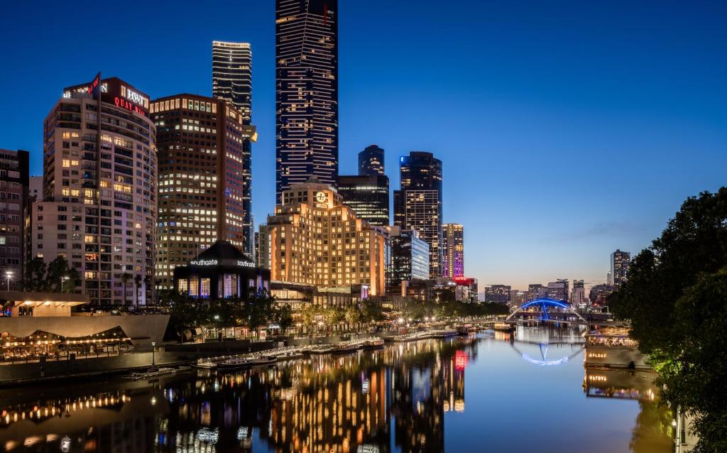 a city skyline at night with a river and buildings at The Langham Melbourne in Melbourne