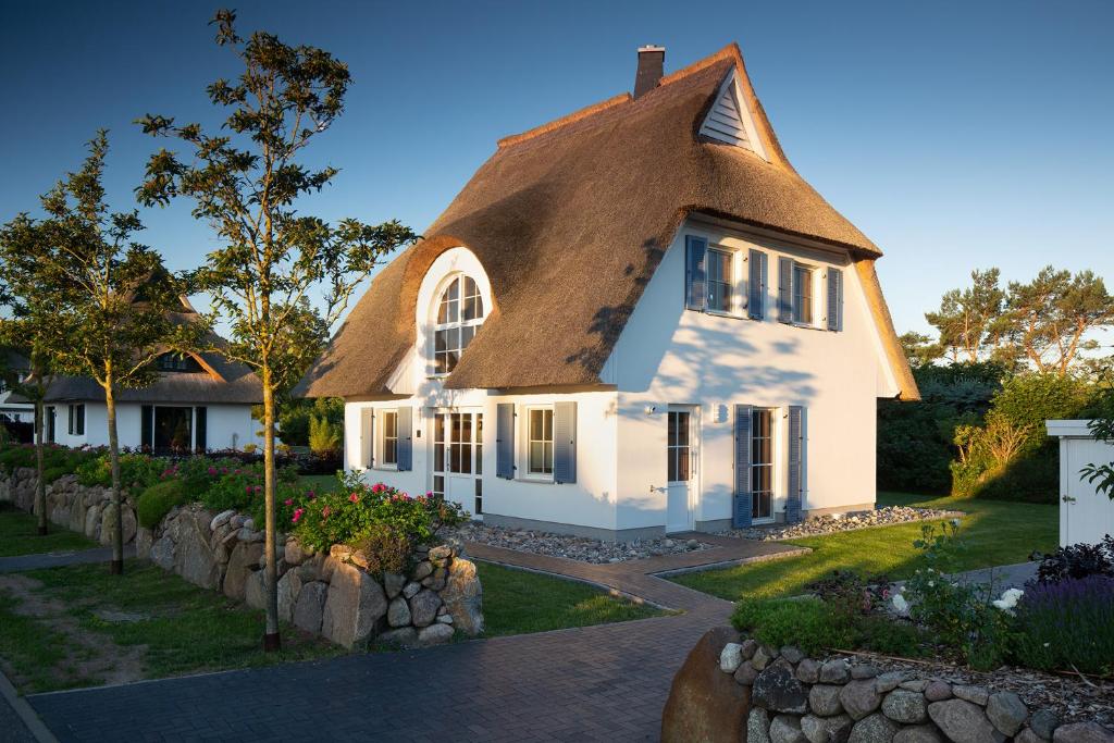 a house with a thatched roof and a stone wall at Ferienhaus Schilfrohrsaenger 51 in Fuhlendorf