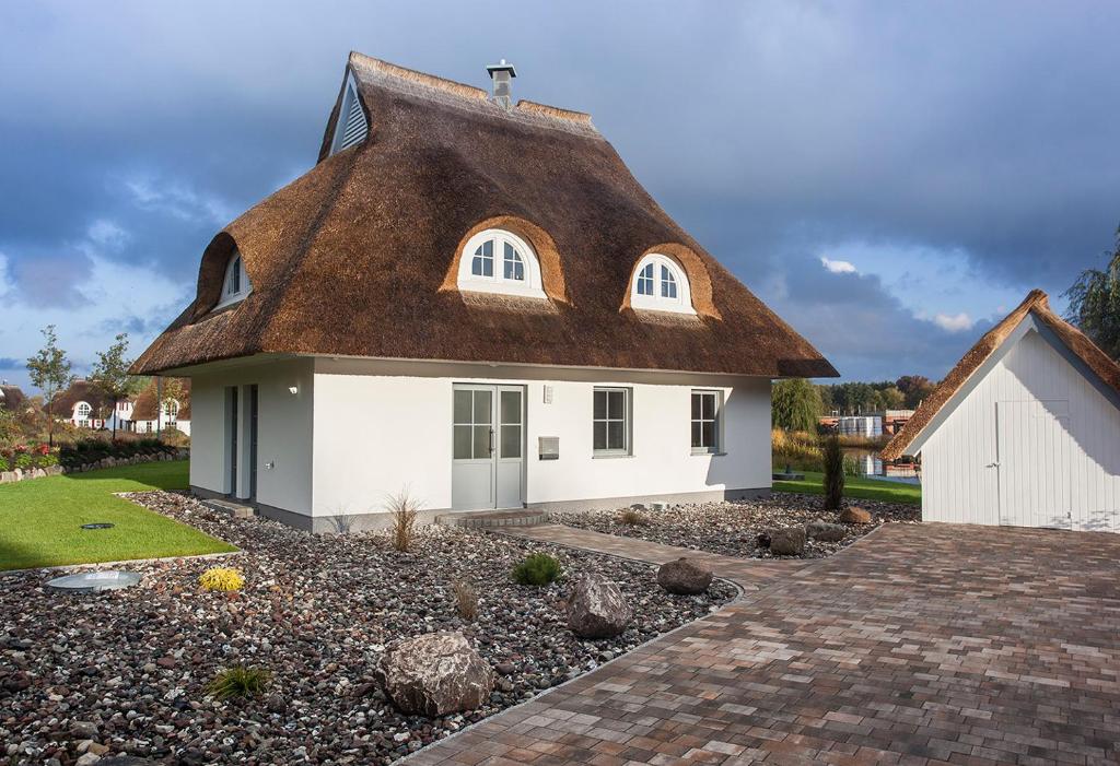 a thatched roof house with a driveway at Ferienhaus Haubenlerche 40 in Fuhlendorf