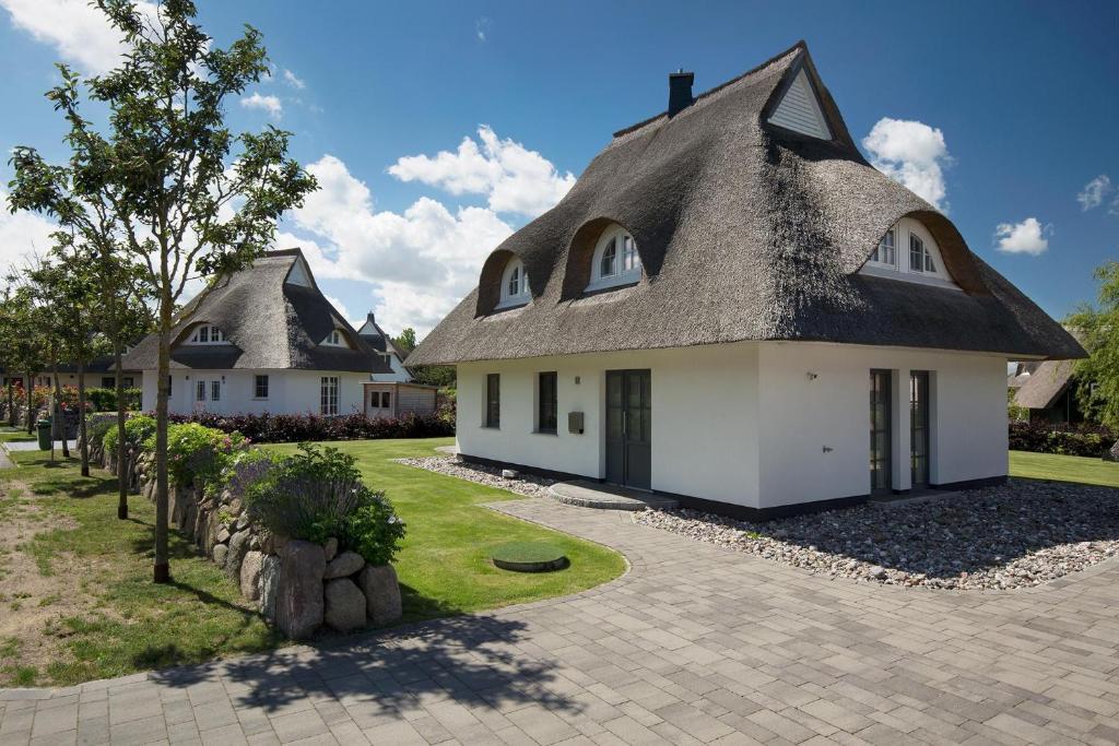 a house with a thatched roof and a driveway at Ferienhaus Haubenlerche 25 in Fuhlendorf