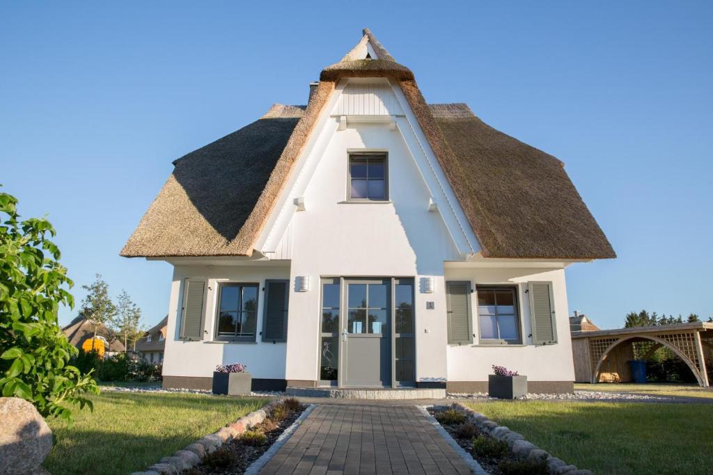 a small white house with a thatched roof at Ferienhaus Seeschwalbe 55 in Fuhlendorf