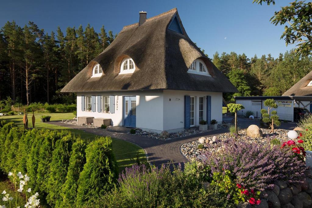 a cottage with a thatched roof in a garden at Ferienhaus Haubenlerche 16 in Fuhlendorf