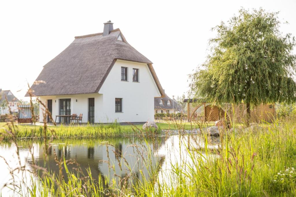 a white house with a pond in front of it at Ferienhaus Seeschwalbe 37 in Fuhlendorf