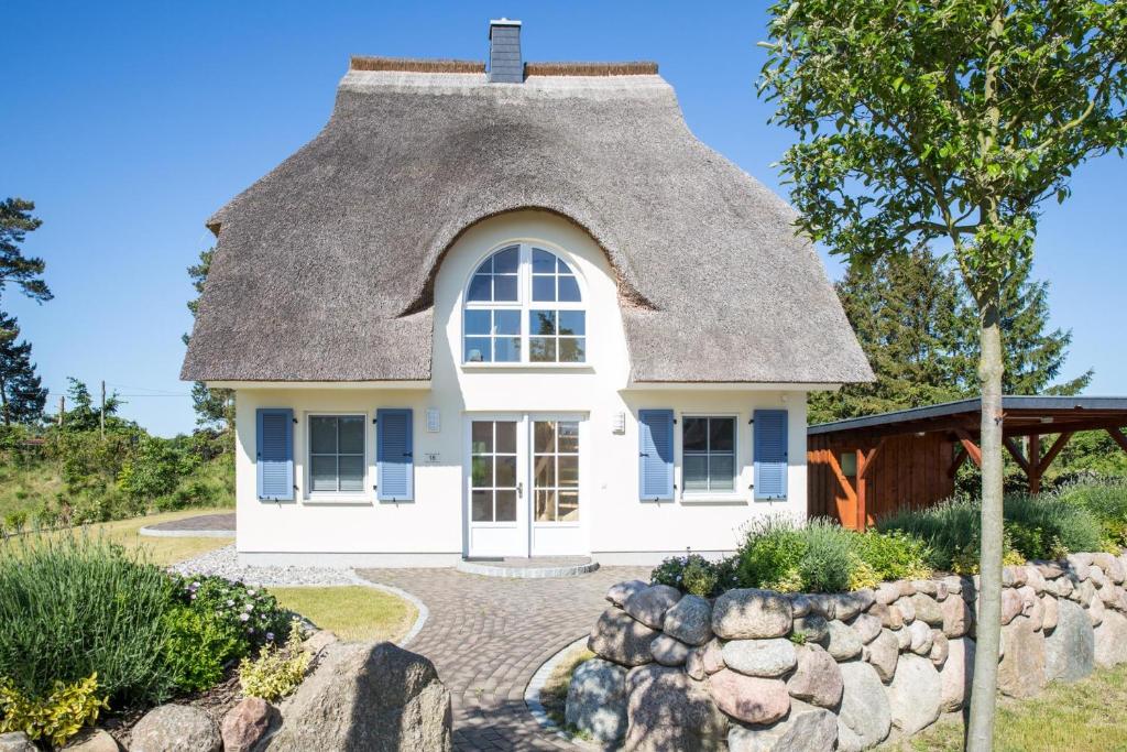 a small white house with a thatched roof at Ferienhaus Schilfrohrsaenger 48 in Fuhlendorf