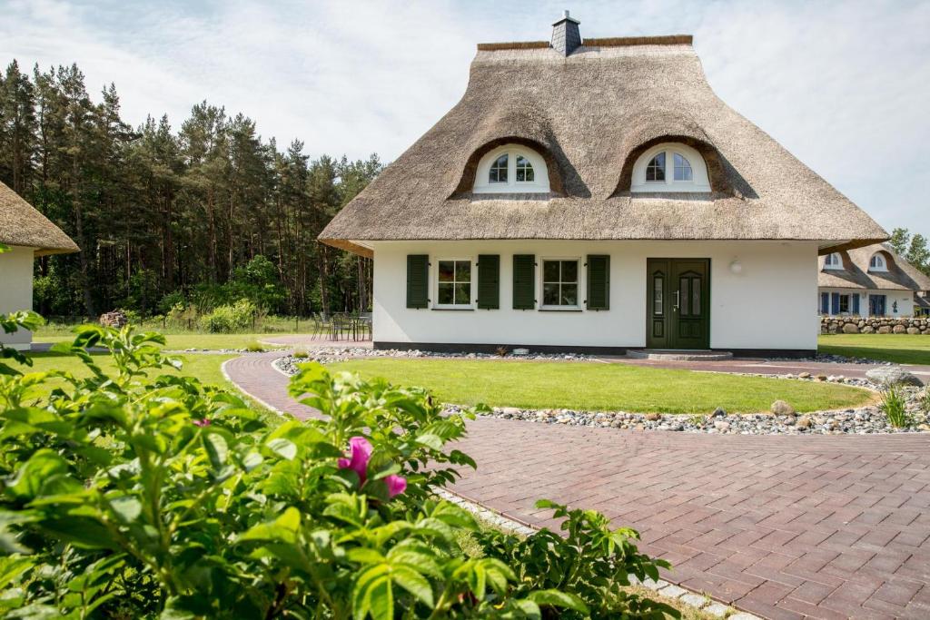 a house with a thatched roof and a driveway at Ferienhaus Haubenlerche 14 in Fuhlendorf