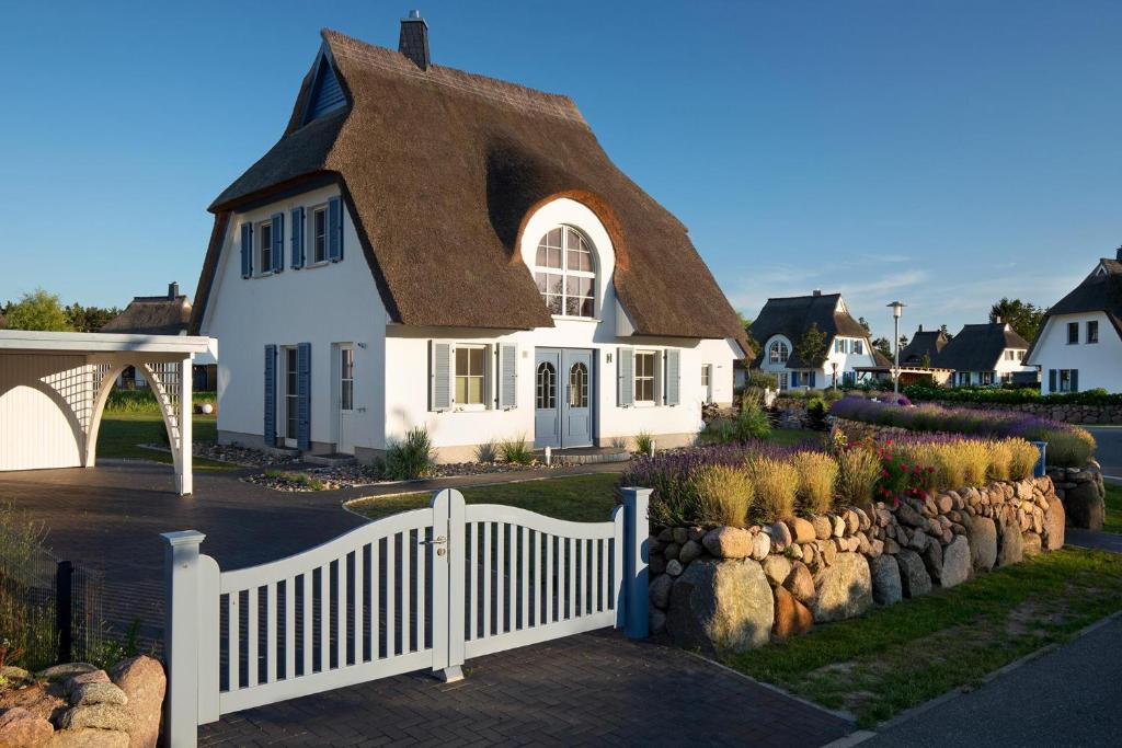 a white house with a brown roof and a fence at Ferienhaus Schilfrohrsaenger 30 in Fuhlendorf