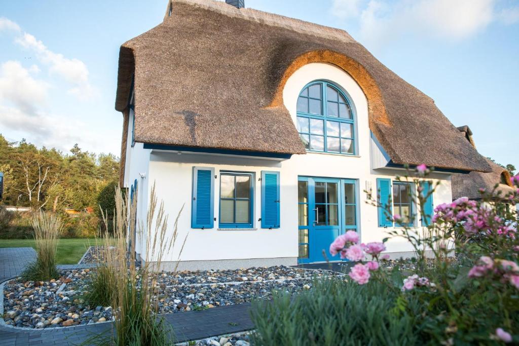 a cottage with a thatched roof and a garden at Ferienhaus Schilfrohrsaenger 8 in Fuhlendorf