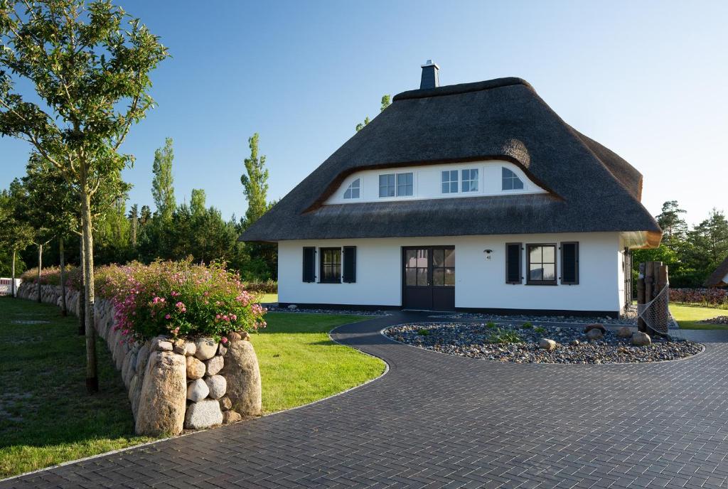 a white house with a black roof and a driveway at Ferienhaus Graukranich 41 in Fuhlendorf