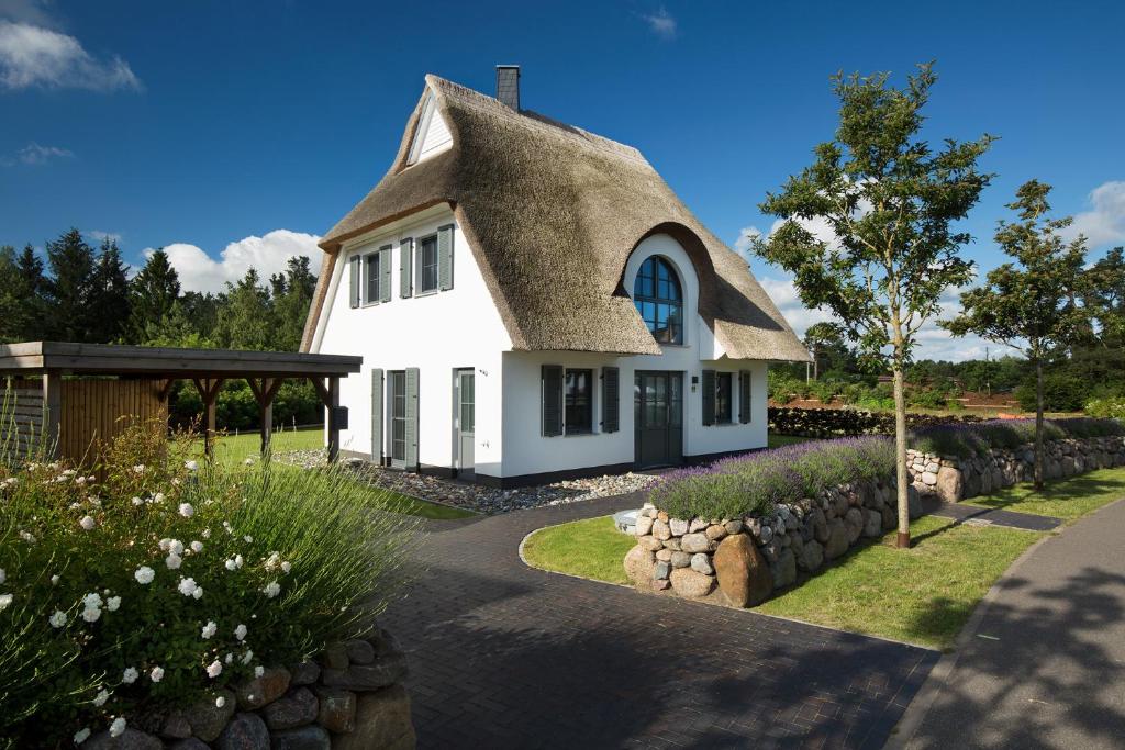 a cottage with a thatched roof and a driveway at Ferienhaus Schilfrohrsaenger 45 in Fuhlendorf