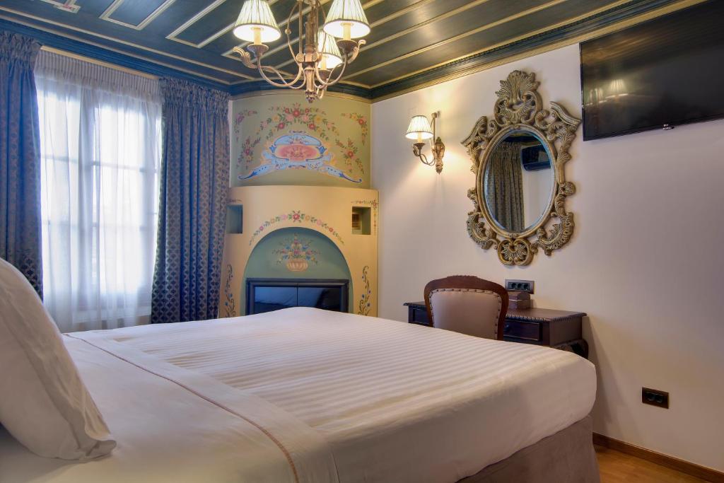 a bedroom with a large bed and a mirror at ARCHONTARIKI Historic Boutique Hotel in Ioannina