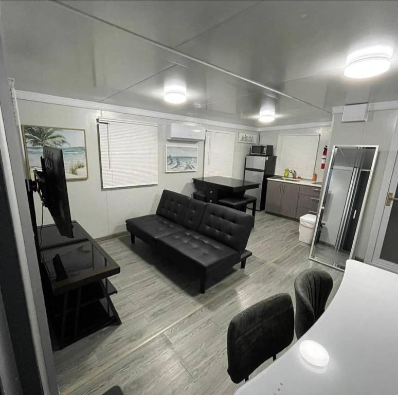 a living room with a black couch and a kitchen at Las Casitas de Village in Carolina