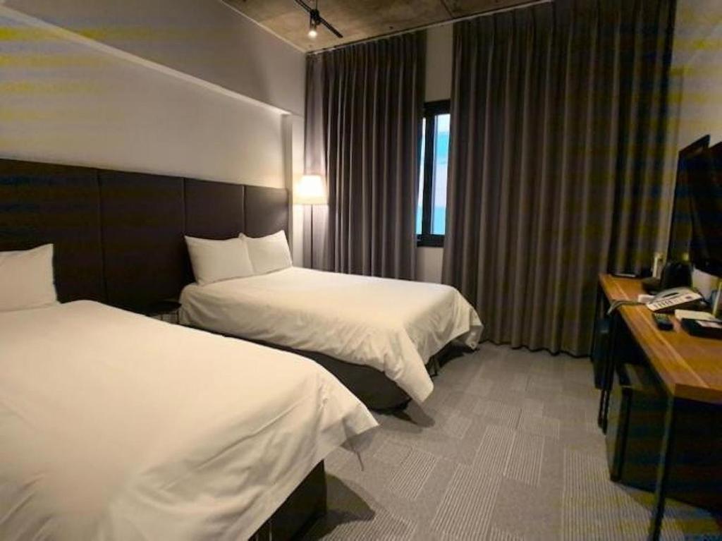 済州市にあるJeju Renaissance Hotelのベッド2台とデスクが備わるホテルルームです。