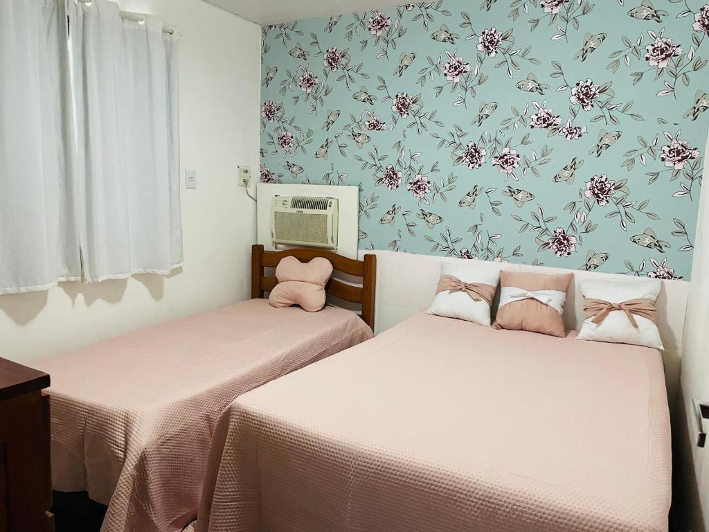 Duas camas num pequeno quarto com papel de parede floral em Condomínio Portais do Francês- Apto - PRAIA DO FRANCÊS/AL na Praia do Francês