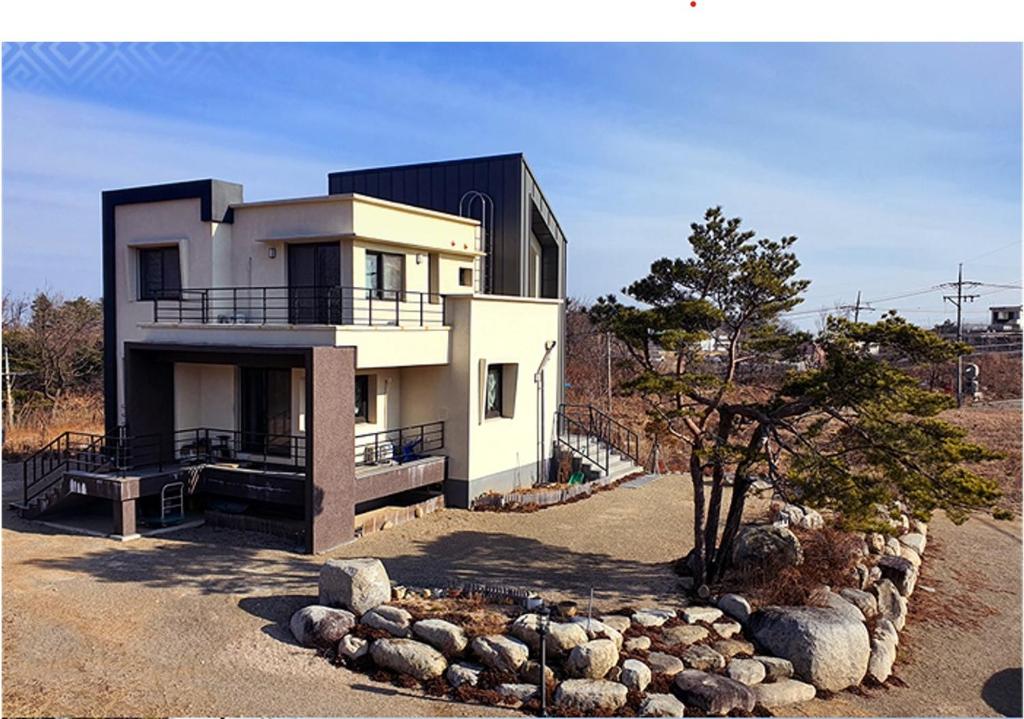 ein großes weißes Haus mit einem Baum davor in der Unterkunft Gilson Guesthouse in Sokcho