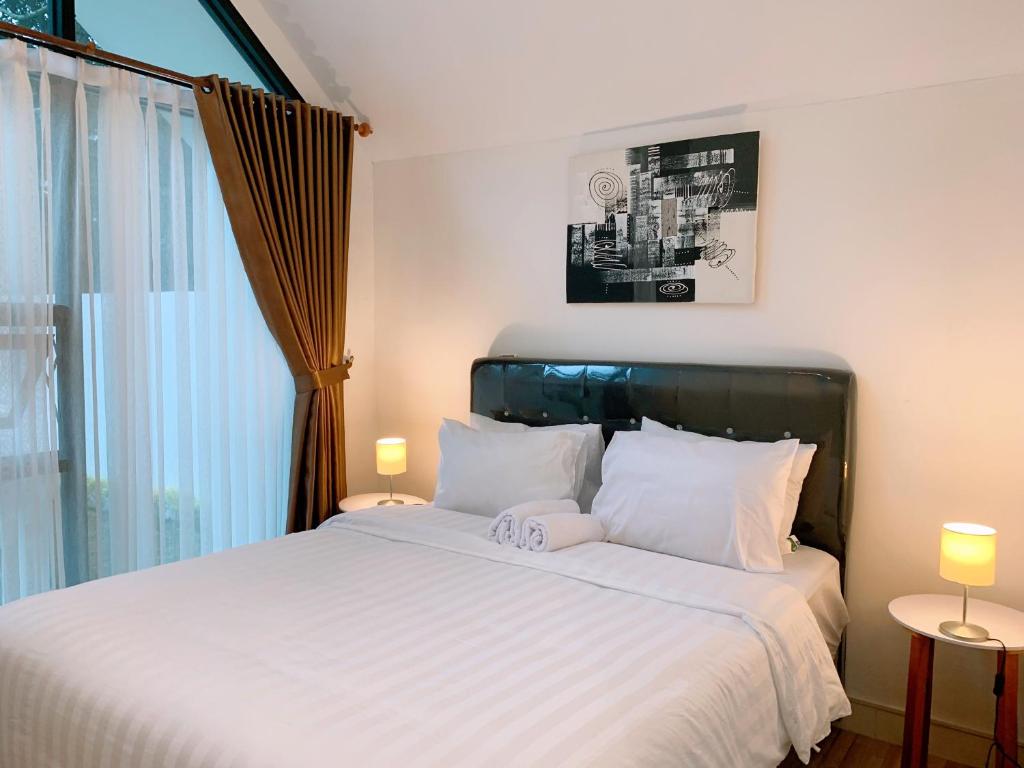 ein Schlafzimmer mit einem Bett mit weißen Laken und einem Fenster in der Unterkunft Casa de Gaudi Lembang in Lembang