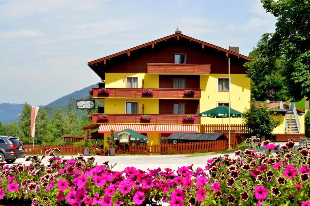 een geel gebouw met bloemen ervoor bij Hotel Beretta in Achenkirch