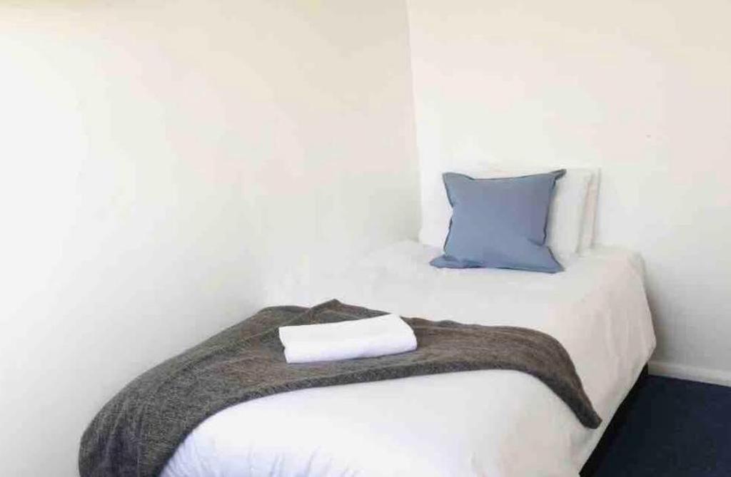 a white bed with a blanket and a blue pillow at Arbnb Comfy Sleep Guest House Self Catering Private Bedrooms 60 pound per night per person in London