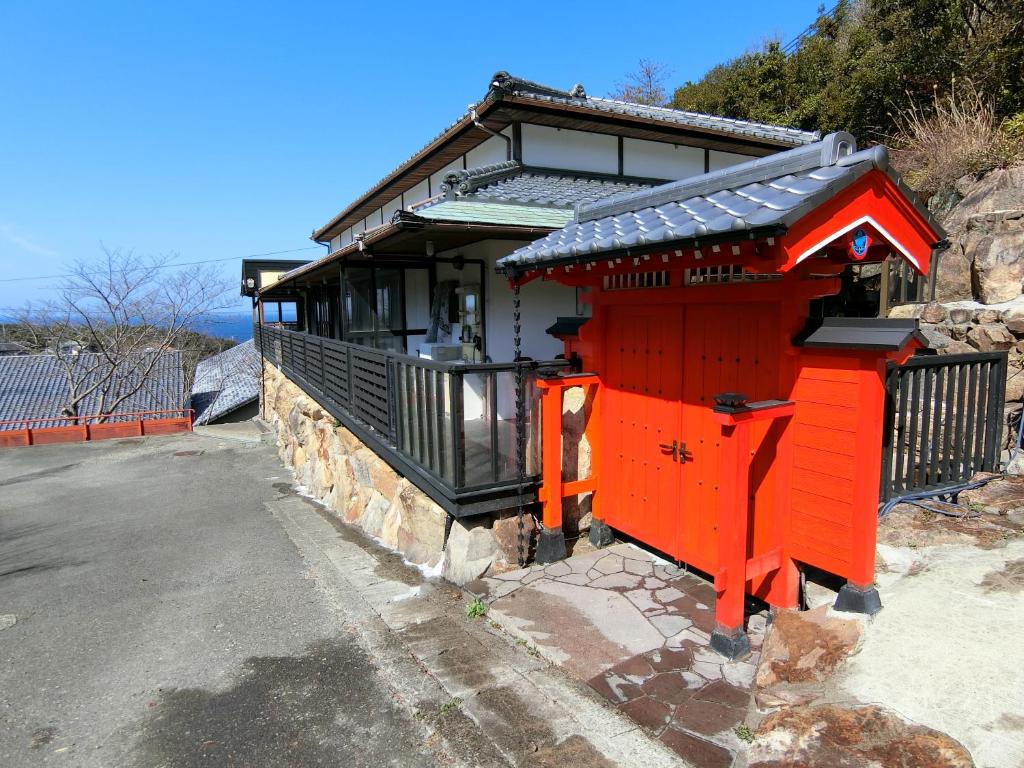 um pequeno edifício vermelho no lado de uma estrada em Shirahama Meiji Villa em Shirahama