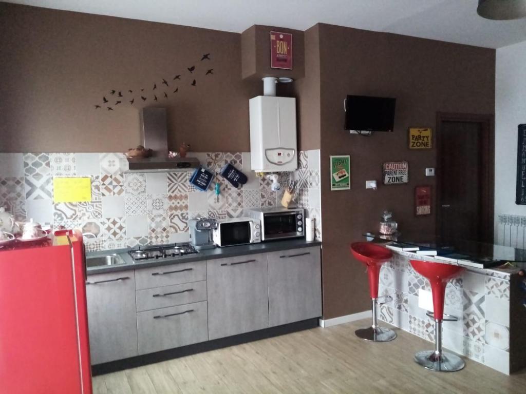 a kitchen with two red stools in a kitchen at Emmanueli65 fronte clinica per 4 matrimoniale e castello in Piacenza