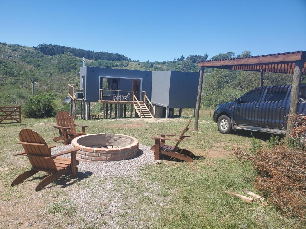 eine Feuerstelle mit zwei Stühlen und einem Truck im Hof in der Unterkunft casas kiran y kanu in Villa Serrana