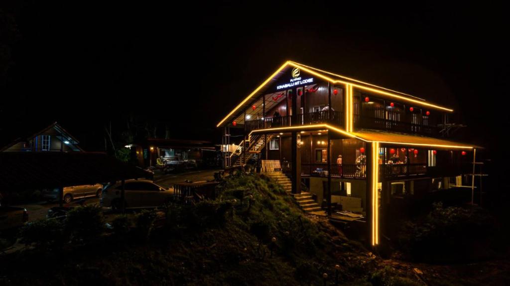 a building with a bar with lights on it at night at Flypod . Kinabalu Mt Lodge in Ranau
