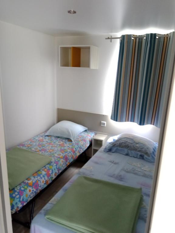 Saint-Aubin-le-CaufにあるMobil home saint aubinのベッド2台と窓が備わる小さな客室です。