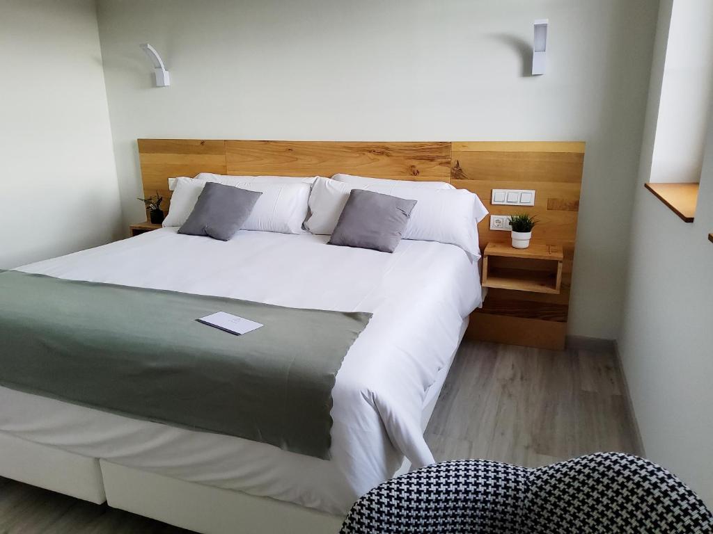 a bedroom with a large white bed and a chair at Hotel Marqués de Aguilar in Aguilar de Campóo