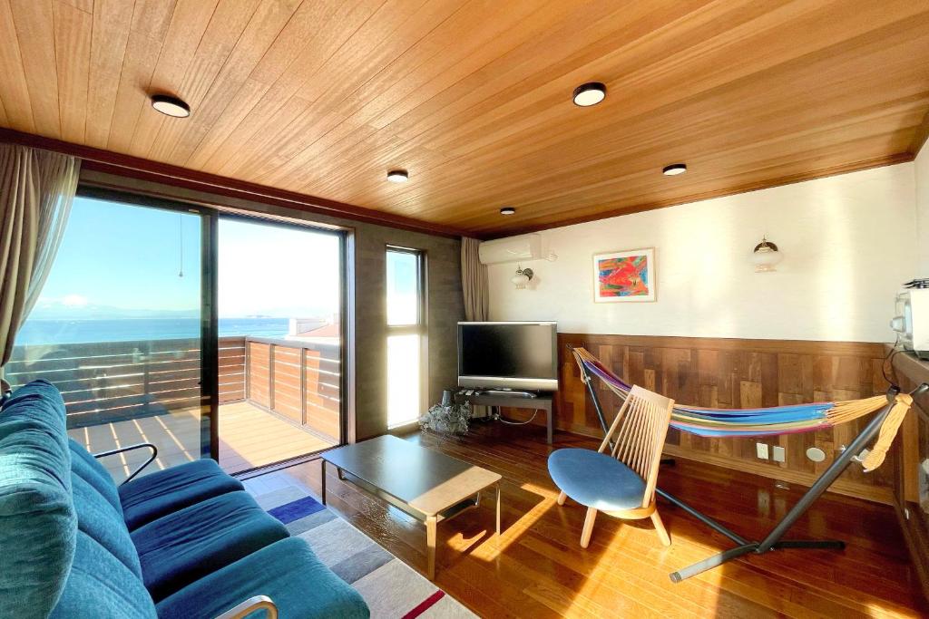 uma sala de estar com um sofá azul e uma rede de descanso em Hayama Ocean View Villa -葉山 海を見渡す家- em Hayama