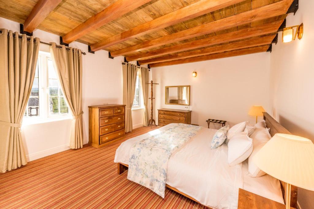 a bedroom with a large bed and a wooden ceiling at Tudor Barn - Little England Cottages in Nuwara Eliya